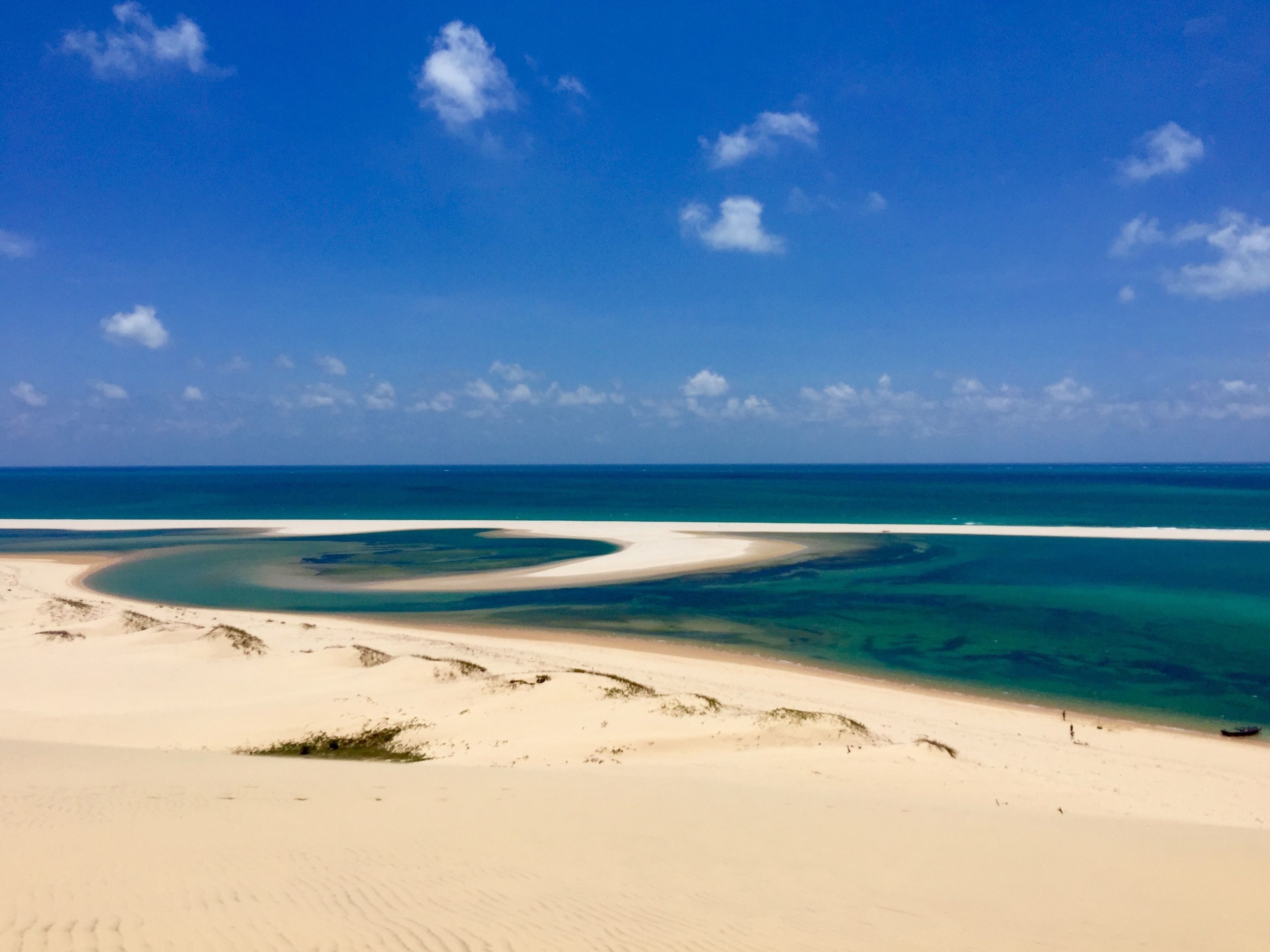 A beach with a clear blue sky and calm sea.