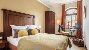 A hotel room with a large bed, a desk with a computer, a chair, and a wardrobe.