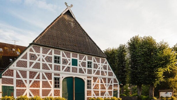 A traditional half-timbered barn with a steep gabled roof and a green door. - Landhaus Zum Lindenhof (Marxen)