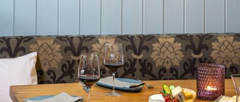 A wooden table with a cheese board, wine glasses, and a candle.
