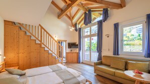 A bedroom with a wooden staircase, a sofa, and a dining table with fruit. - Gartenheim B&B Tramin (Termeno Sulla Strada del Vino)