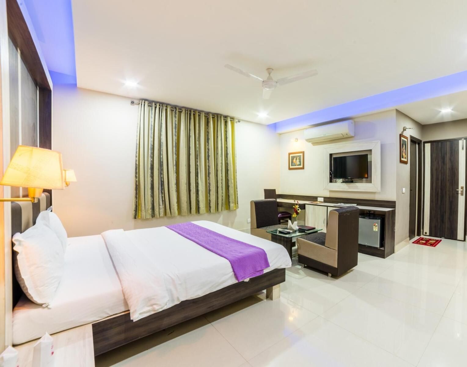 A hotel room with a bed, a desk, a TV, and a wardrobe.
