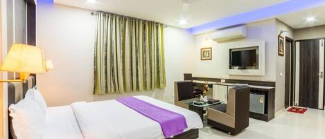 A hotel room with a bed, a desk, a TV, and a wardrobe.