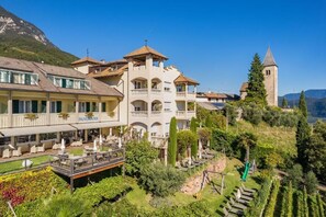 A hotel with multiple balconies, a restaurant named 'PANORAMA,' and a tower in the background. - Panorama Tramin (Termeno Sulla Strada del Vino)