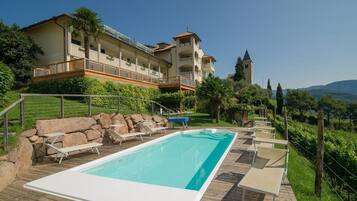 Un resort con piscina, sillas de descanso y vistas a la montaña.