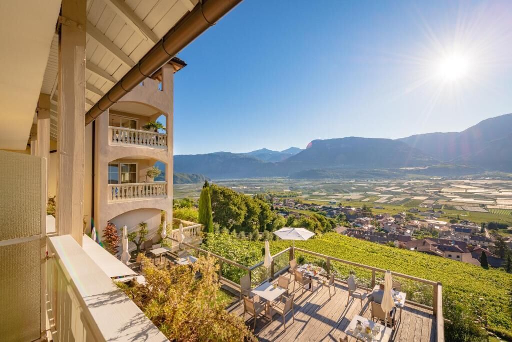 A terrace with outdoor seating overlooking a vineyard and a valley.