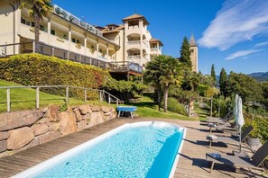 A hotel with a swimming pool, lounge chairs, and a view of the surrounding landscape. - Panorama Tramin (Termeno Sulla Strada del Vino)