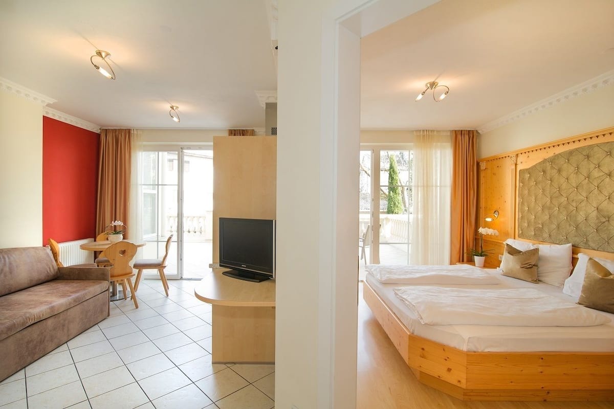 Una habitación de hotel con cama, sofá, televisión y escritorio con silla.