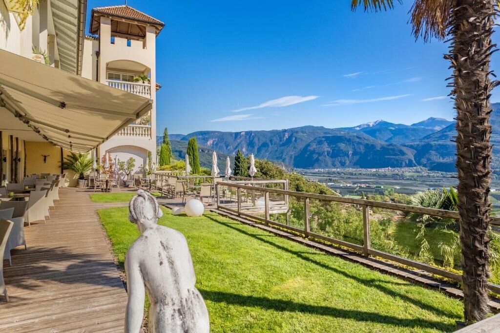 Hotel con terraza al aire libre, una estatua y vistas a las montañas.