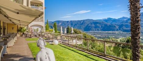 Hotel con terraza al aire libre, una estatua y vistas a las montañas.