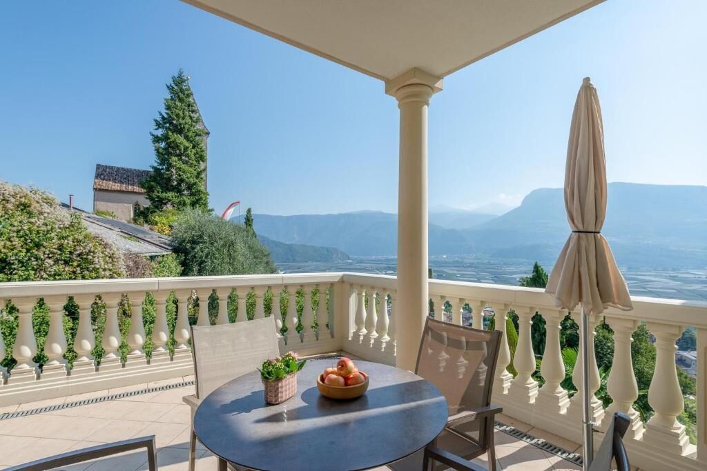 A balcony with a table, chairs, and a bowl of fruit.