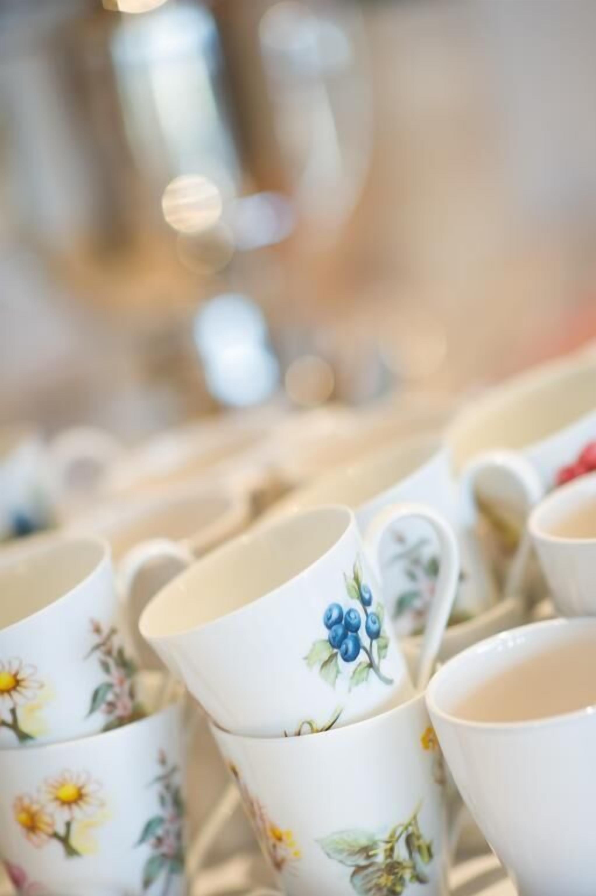 Una colección de tazas de cerámica blanca con diseños florales, dispuestas en una estantería.