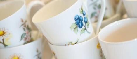 Una colección de tazas de cerámica blanca con diseños florales, dispuestas en una estantería.