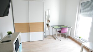 A modern, minimalistic room with a desk, chair, and a large window.