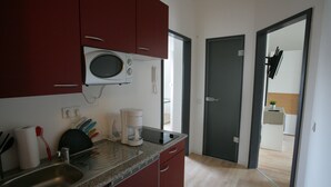 A modern kitchen with red cabinets, a built-in microwave, and a coffee maker.