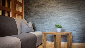 A modern living room with a grey sofa, a wooden coffee table, and a grey potted plant.