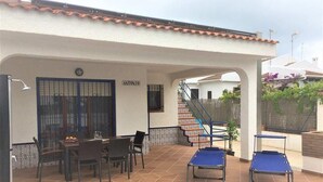 Un espace extérieur abrité comprenant une piscine, une table à manger avec des chaises et un escalier menant à un niveau supérieur.
