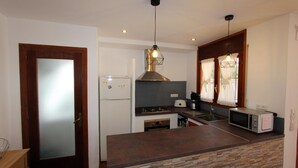 Une cuisine dotée d’un îlot central, d’un réfrigérateur, d’une cuisinière, d’un four à micro-ondes et d’un luminaire suspendu.