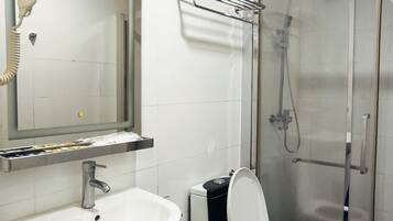 Un baño con lavamanos, inodoro y cabina de ducha de vidrio.