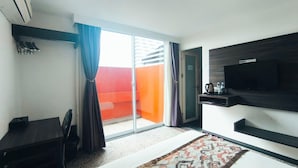 A hotel room with a bed, a desk, a TV, a coffee maker, and a sliding glass door to the outside. - Natol Hotel (Kuching)