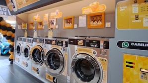 A laundromat with multiple washing machines, a price list, and promotional signs. - Natol Hotel (Kuching)