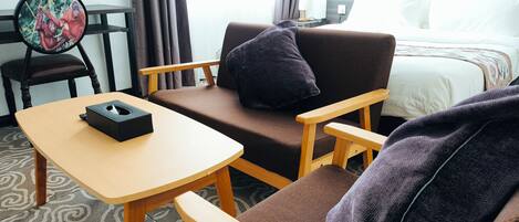 A hotel room with a bed, a sofa, a small table, and a chair.