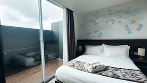 A hotel room with a large bed, a wooden floor, a glass door leading to a balcony, and a colorful wall mural. - Natol Hotel (Kuching)