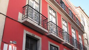 Edificio de un hostal rojo y blanco con balcones y rejas en las ventanas.