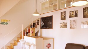 Un interior moderno con una escalera que sube a un segundo piso, una zona de bar con taburetes y un sofá.