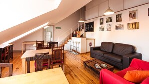 Un espacio habitable tipo loft con comedor, sofá y una escalera que lleva a un nivel superior.