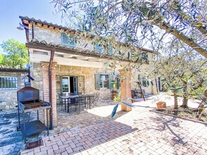 A stone building with a patio, outdoor seating, and a grill.