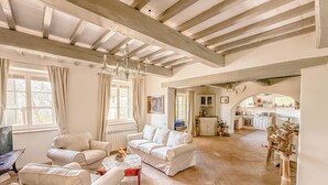 Amplia sala de estar con techos altos, chimenea y vista a la cocina.