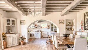 Una cocina amplia con un arco que da a un comedor, que presenta una mesa y sillas de madera.