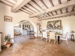 A spacious dining area with a high ceiling, exposed beams, and a chandelier.