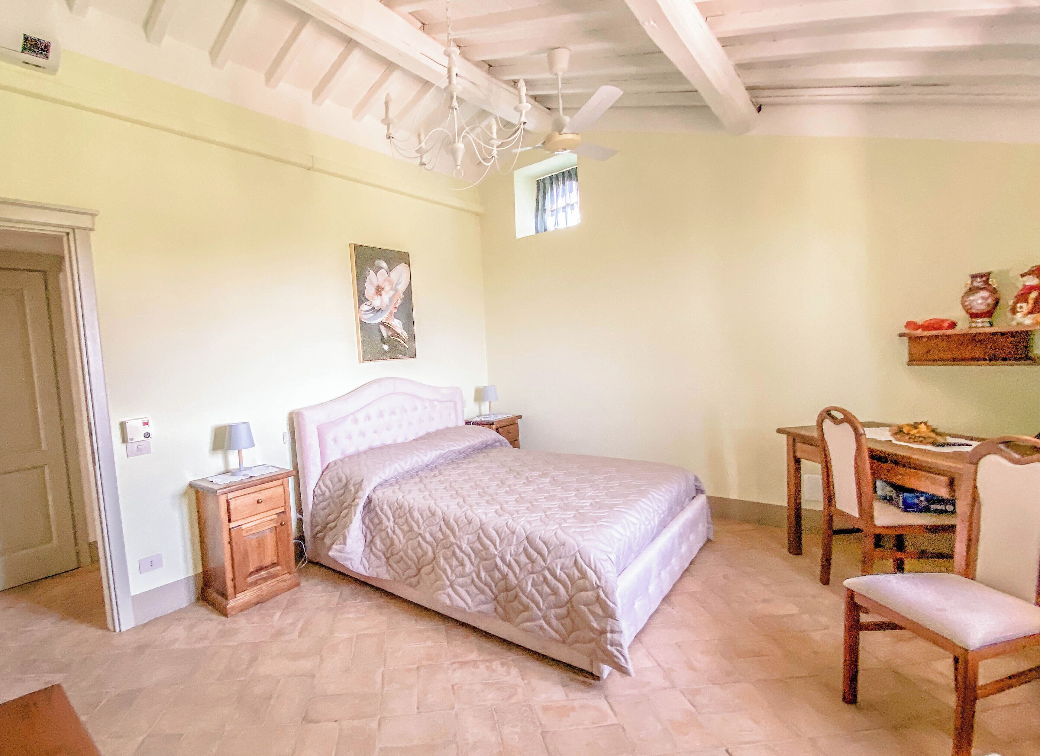 A bedroom with a bed, bedside tables, a desk, and a chair.