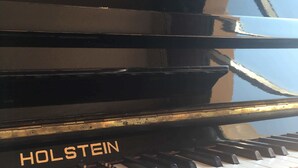 A black piano with the brand name "HOLSTEIN" on the side. - Hôtel Avocado (Saint-Jeannet)