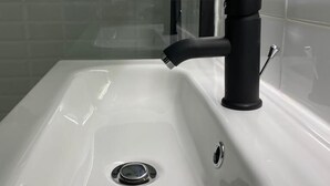 A bathroom with a white sink, black faucet, and a glass shelf above the sink. - Hôtel Avocado (Saint-Jeannet)