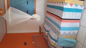 A room with a hammock, a bed with a patterned blanket, and a blue door. - ti case gwada bungalow rentals "ti dauphin" (Sainte-Anne)
