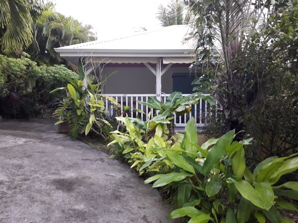 A house with a white porch, surrounded by lush greenery. - ti case gwada bungalow rentals "ti dauphin" (Sainte-Anne)