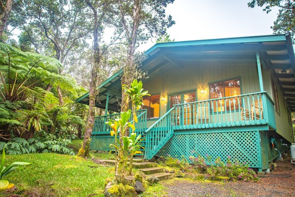 A turquoise building with a balcony, surrounded by lush greenery and trees. - 6 mins from Nat'l Park! Enjoy the sound of rain & birds in a peaceful retreat. (Volcano)