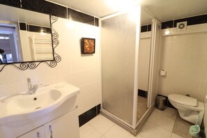 A bathroom with a white sink, a toilet, and a shower enclosure. - Miray Apart Hotel (Istanbul)