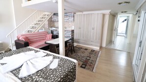 A bedroom with a bed, a desk, a chair, and a staircase.