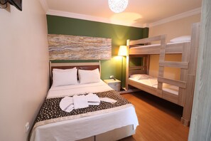 A hotel room with a large bed, a smaller bunk bed, a bedside table with a lamp, and a wall art piece. - Miray Apart Hotel (Istanbul)