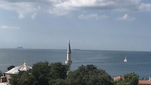 A coastal view with a mosque, a sailboat, and a distant island.
