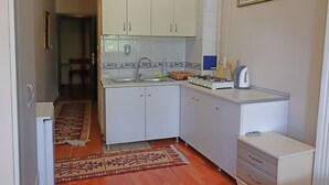 A compact kitchen with white cabinets, a sink, a stove, and a small countertop.