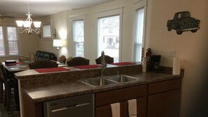 Une cuisine équipée d’un lave-vaisselle intégré, d’un évier et d’un coin repas avec des chaises et une table.