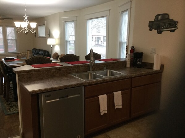 A kitchen with a built-in dishwasher, a sink, and a dining area with chairs and a table.