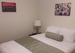 Habitación de hotel con cama, mesita de noche, lámpara y dos obras de arte en la pared.