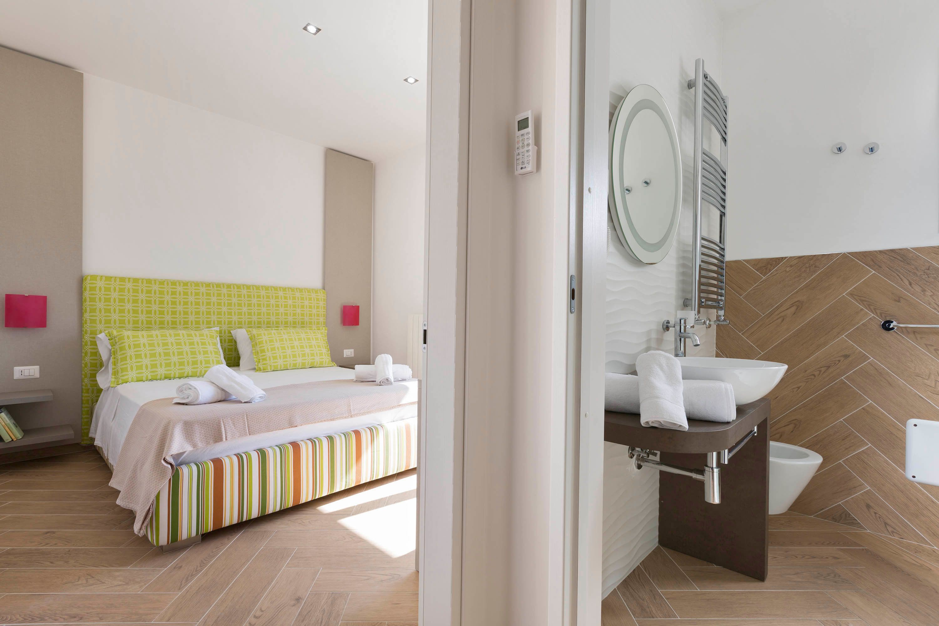 A hotel room with a bed, a bathroom with a sink and mirror, and a shower area.