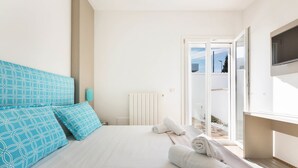 A bedroom with a bed, pillows, a TV, and a view of the outdoors. - Absolute Suite Apartments (Porto Cesareo)